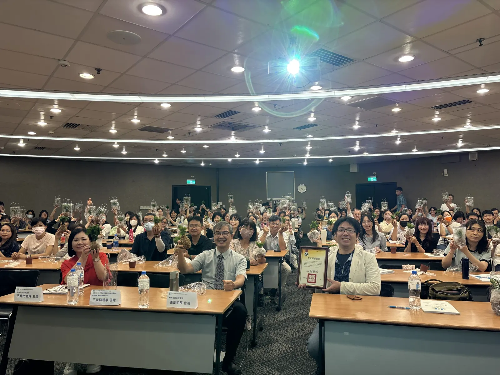 研習結束時，全體學員與講者合影，手中舉著完成的植栽，一旁是教育部的感謝狀